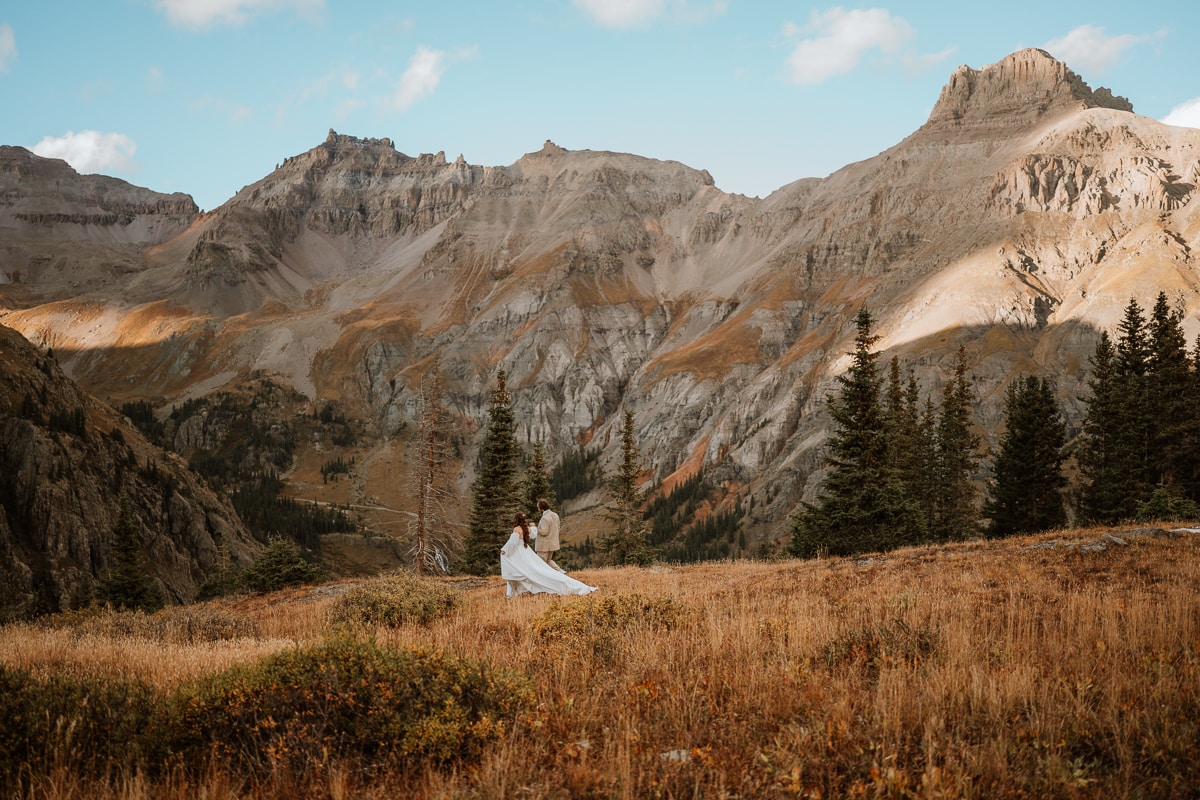 Couple walk hand in hand down a mountainside at sunset for their epic elopement in Ouray, Colorado. When you're writing out your plan for your elopement day, be sure to include time for each other and to enjoy the sunset, just like this couple did.