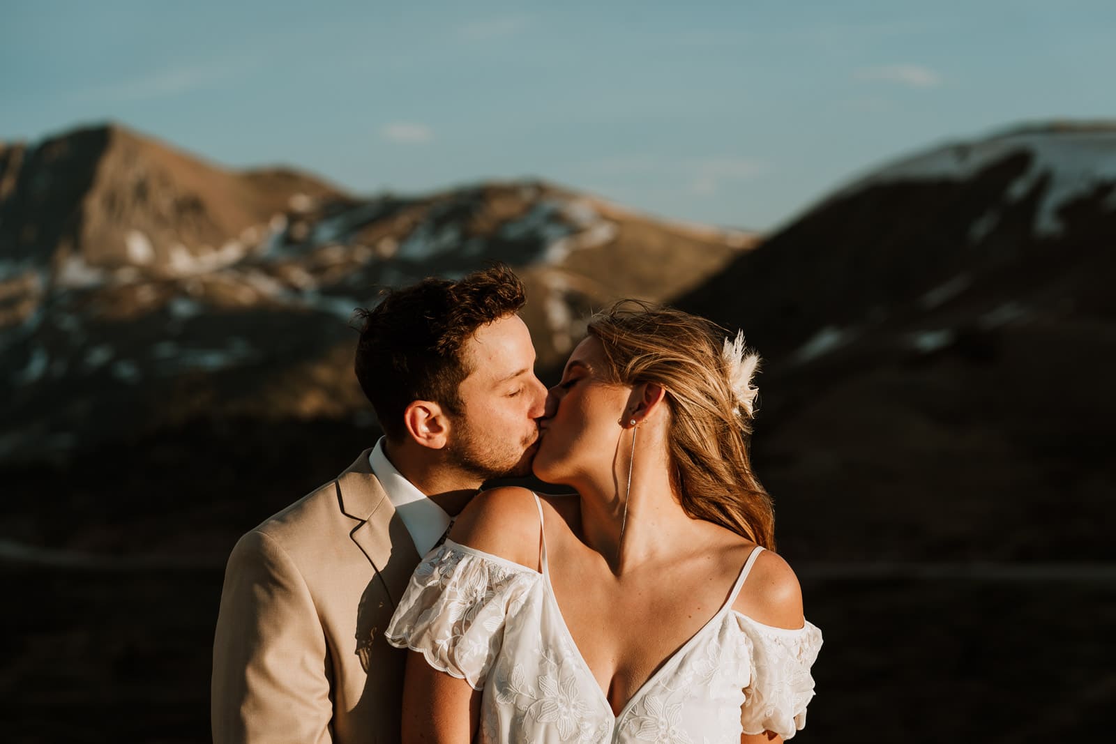 Bride and groom share a kiss at sunset on top of a mountain in Colorado called Loveland Pass
