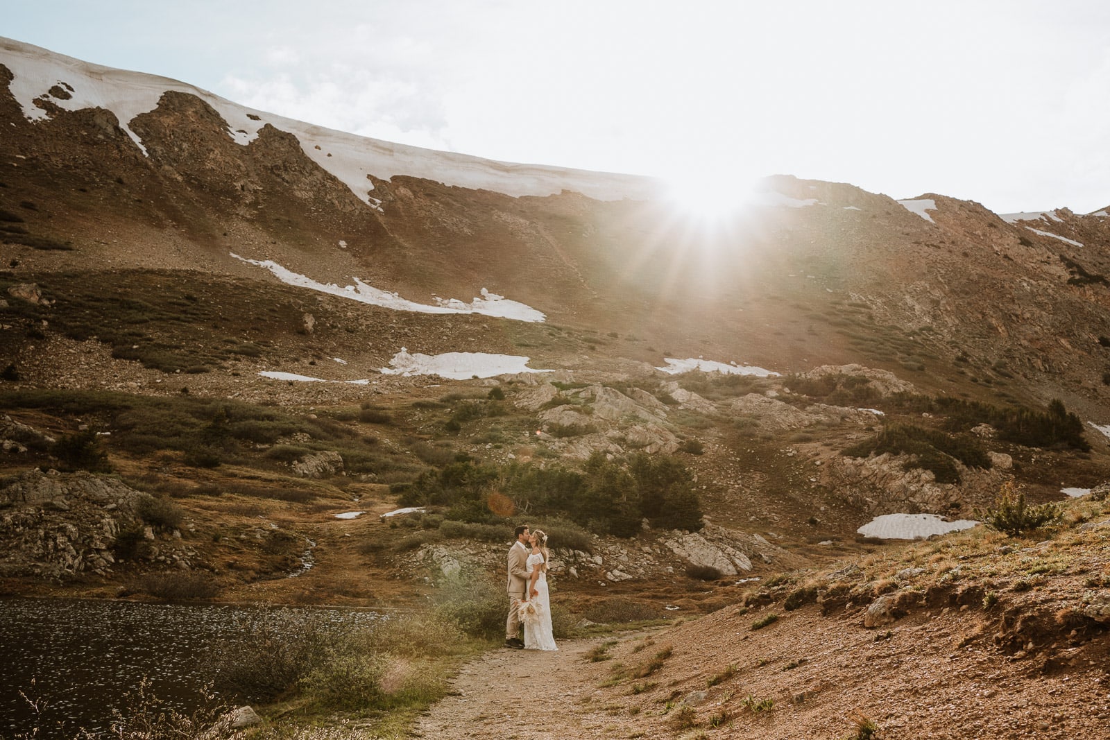 Bride and groom share a kiss with Loveland Pass mountains and the sunset behind them