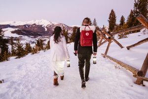 Bride and groom walk to ceremony location in the snow for this winter sapphire point elopement
