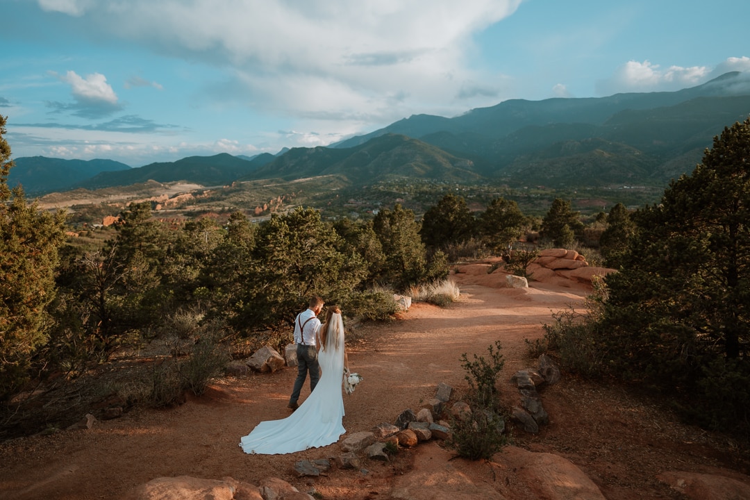 Wedding couple walk together on a hiking trail in Garden of the Gods at sunset for their romantic elopement.