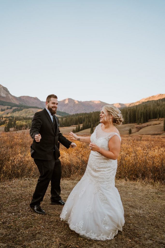 Bride and groom laugh and dance at sunset after eloping in Crested Butte Colorado
