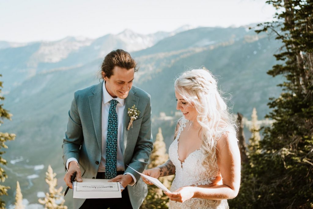 After reading through their custom elopement ceremony script, a couple reads the legal requirements when it comes to self solemnization in Colorado. Mountains are in the background as the sun lights them up.