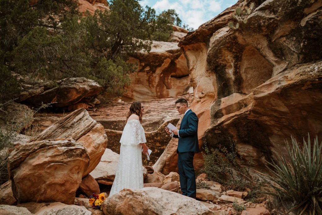 Couple stands among the Red Rocks of Colorado and reads their custom elopement ceremony script and wedding vows to each other.
