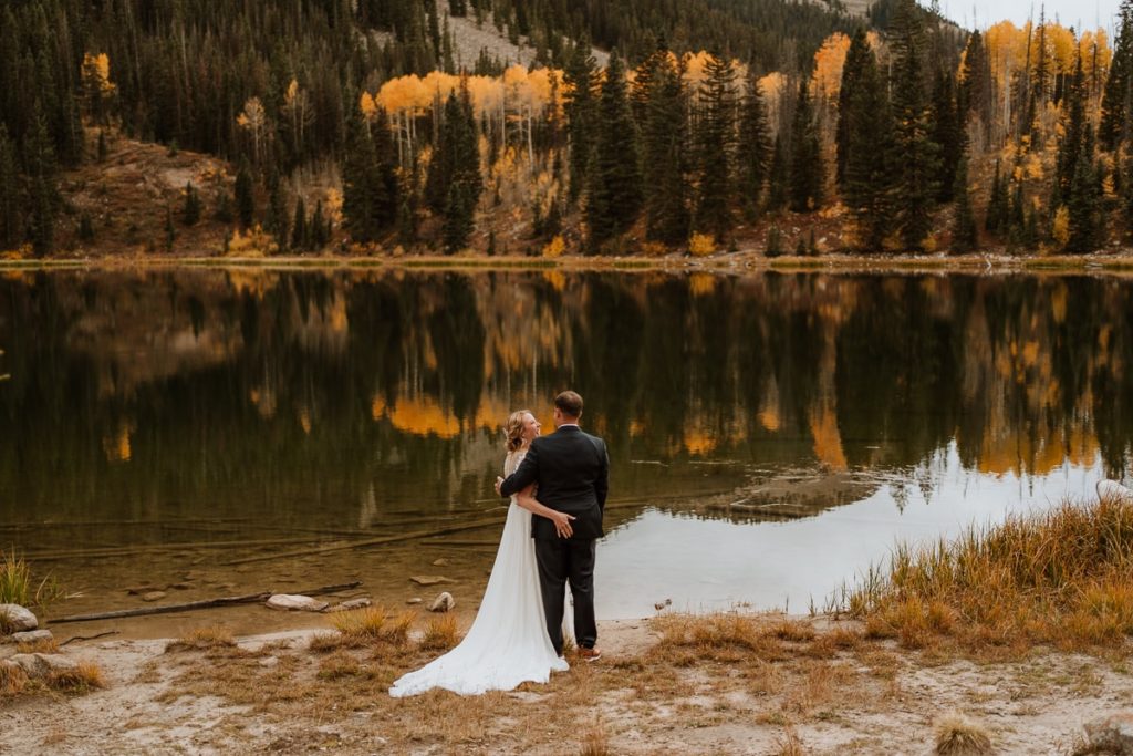 Bride grabs her new husband's butt as they stand in front of the lake and take in all the views.