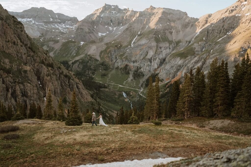Couple eloping in the mountains near Ouray, Colorado during golden hour. The alpenglow glows bright on the tall mountains behind them.