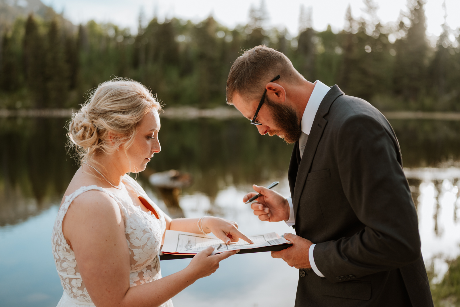 The bride shows the groom where to sign for their marriage license to make their marriage legal in the state of Colorado!