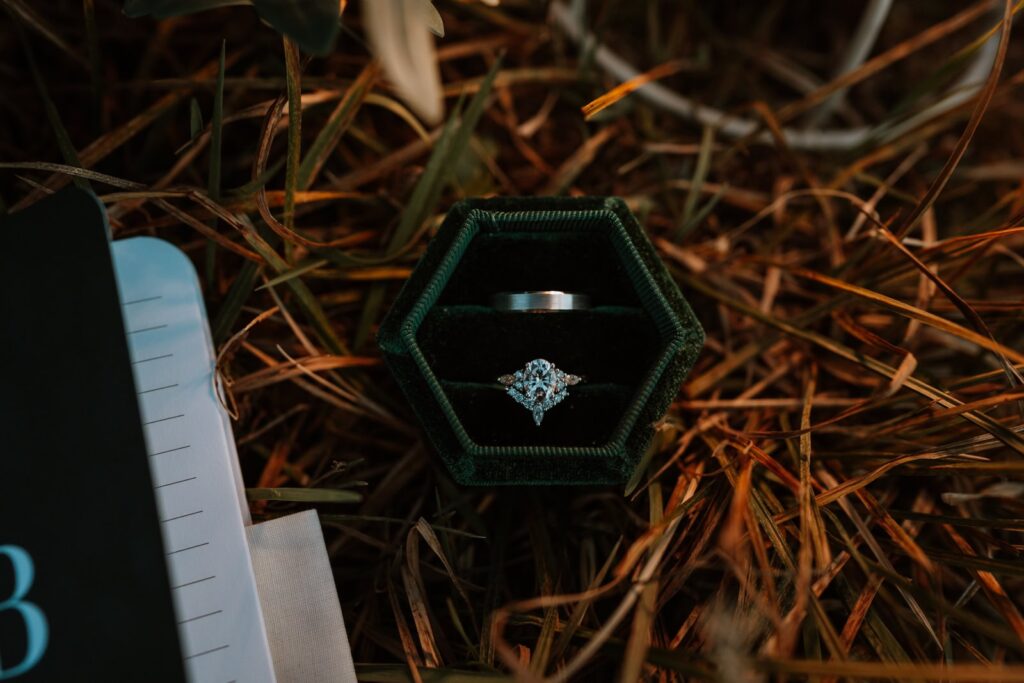 Closeup photo of a bride and groom's wedding ring in an octagon shaped green ring box.