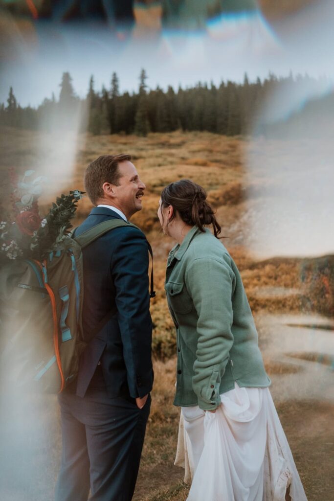 The artistic image shows a lens flare across both sides of the image and the bride and groom laughing together.