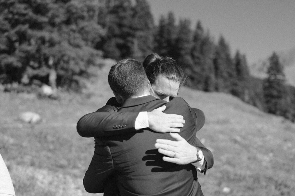Closeup black and white photo of the groom hugging the best man after his emotional speech.