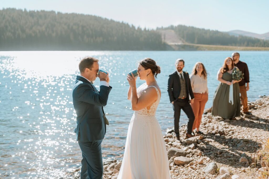 Bride and groom drink from their coffee cups for their unity ceremony as the guests watch in the background.