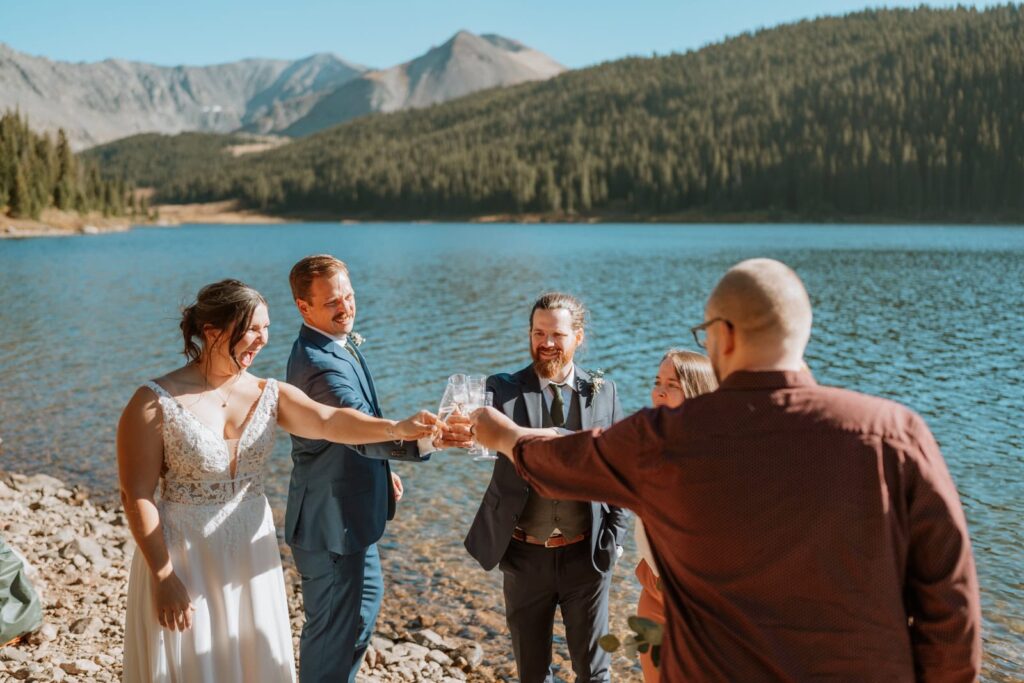Bride and groom toast to their guests with champagne. The mountains are in the background.