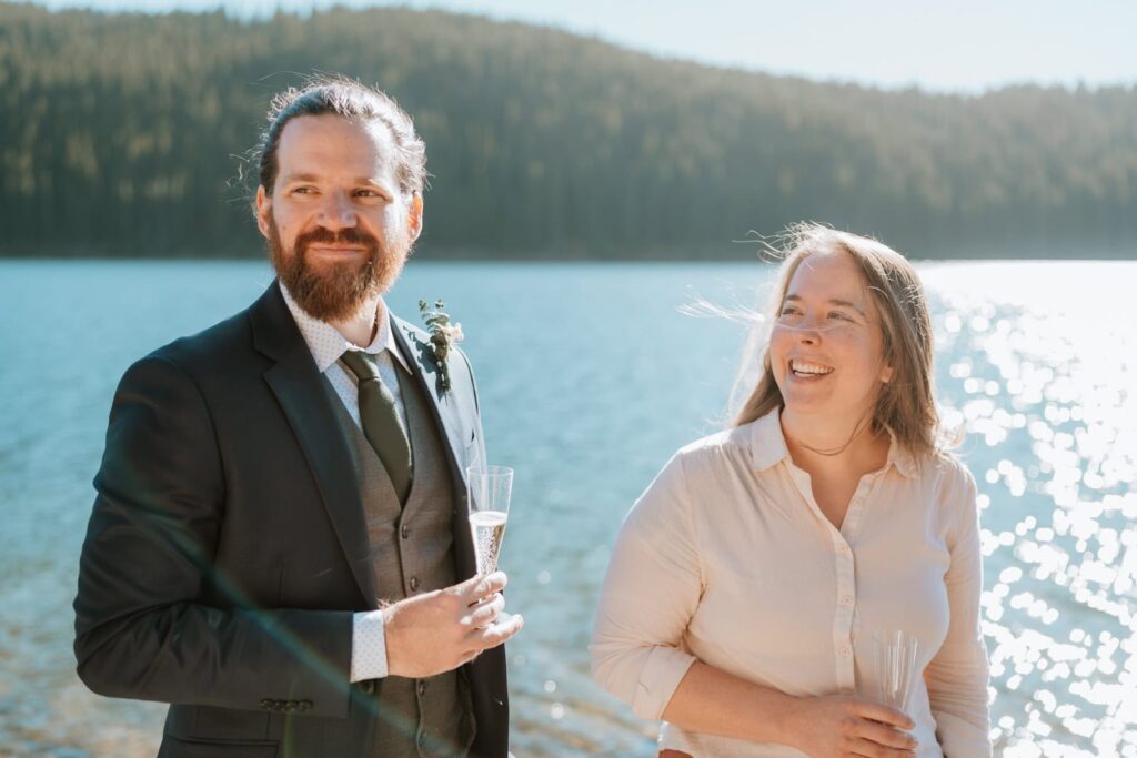 Two of the wedding guests smile and laugh as they hold a glass of champagne.