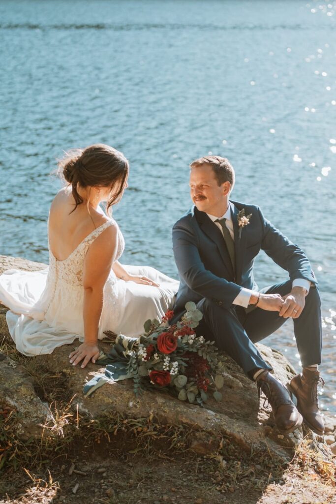Bride and groom sitting on a large rock together at Clinton Gulch reservoir near Breckenridge and Copper mountain in Colorado.