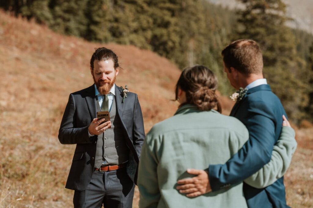 Closer photo of the best man reading his speech with the bride and groom holding each other in the foreground.