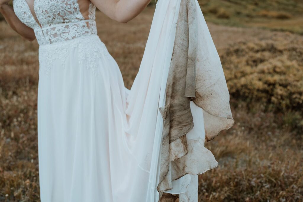 Closeup of a bride's muddy wedding dress, which got dirty from hiking on her adventurous elopement in Colorado.