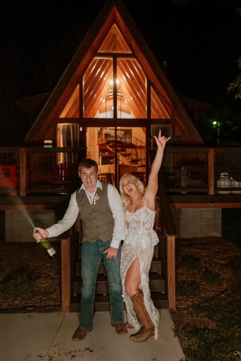 Newlyweds celebrate as they pop champagne in front of their a-frame cabin near Ouray.