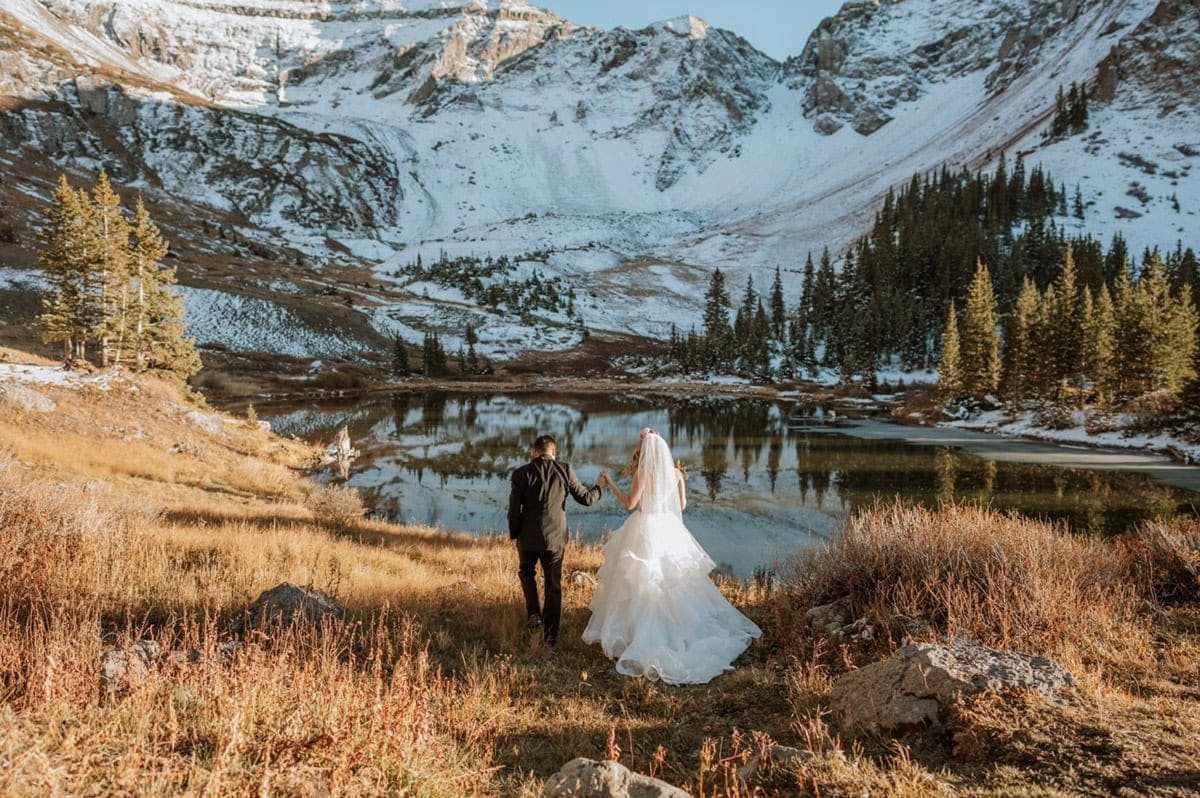 Couple walking hand-in-hand to their Telluride elopement ceremony site surrounded by alpine peaks