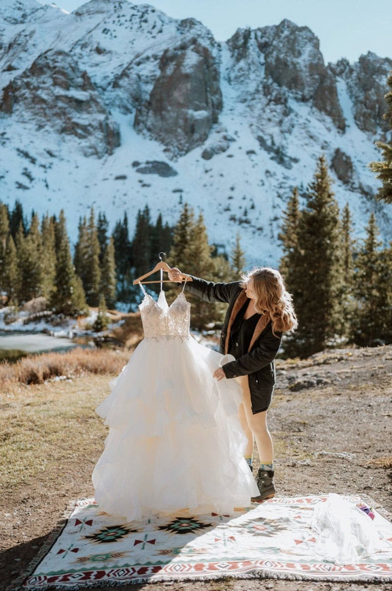 Bride preparing her dress outdoors before a 4x4 elopement in the San Juan Mountains.