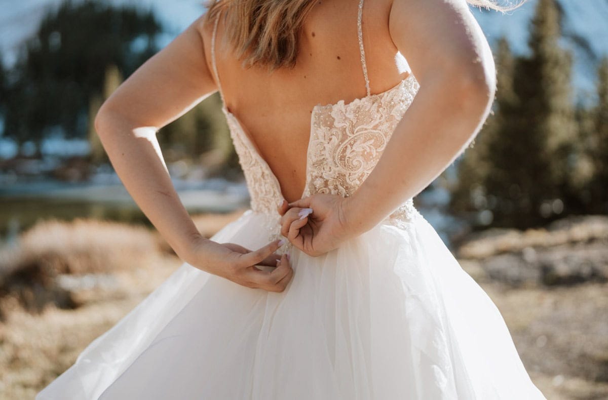 Close-up of bride zipping her gown before a mountain elopement in Colorado