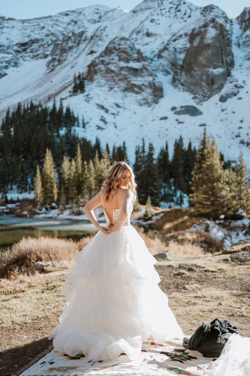 Bride adjusting her gown before a Telluride elopement near an alpine lake