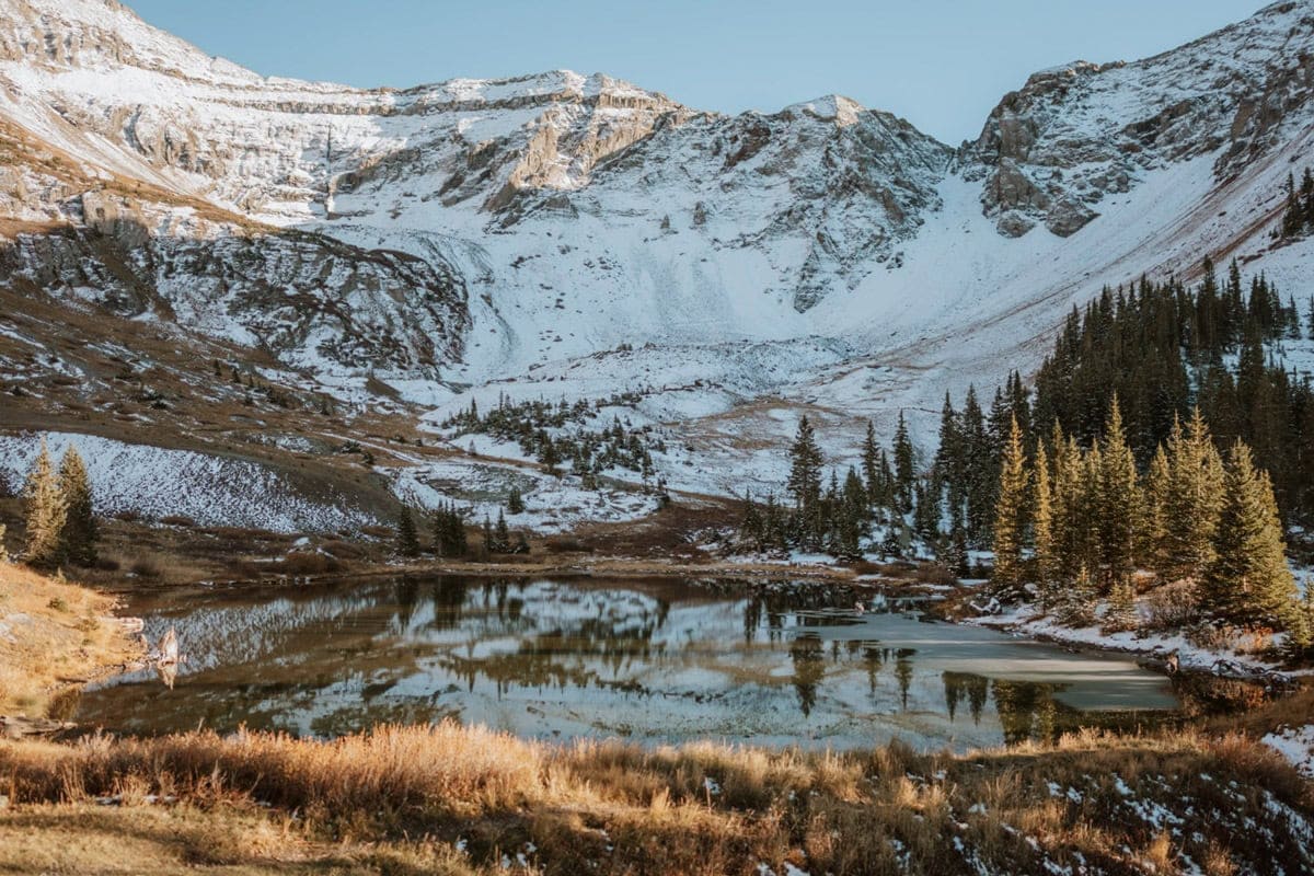 Snowy alpine lake and rugged ridgeline during a San Juan elopement in Colorado