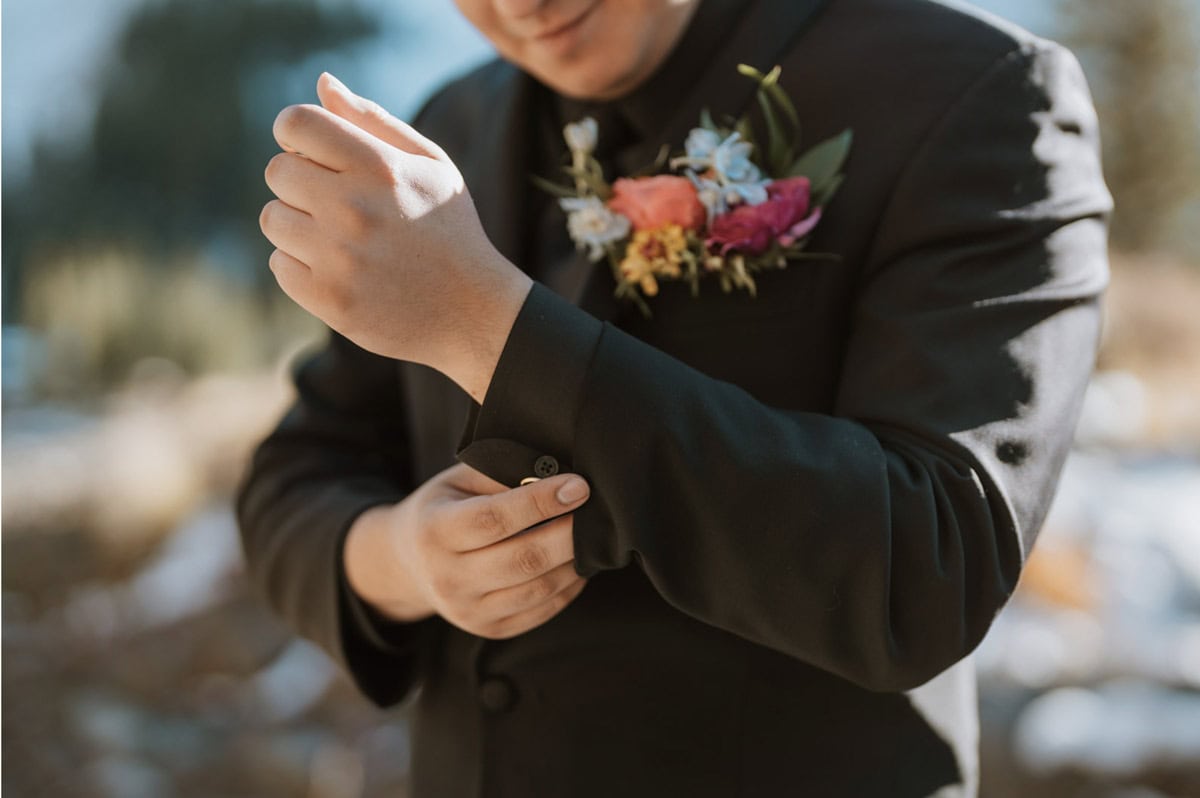 Groom adjusting cuff with boutonniere during an off-road elopement in Telluride