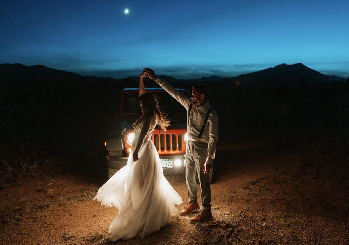 Couple dancing in front of a Jeep under the moonlight after their adventurous celebration, highlighting Colorado elopement packages for adventurous weddings.