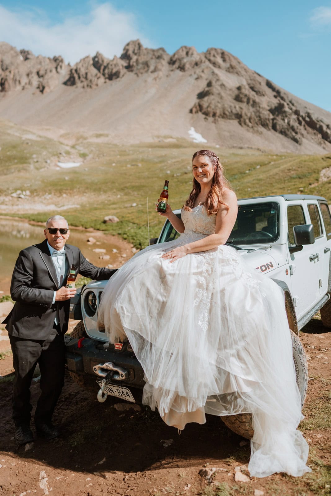 Bride and groom holding beers during a jeep wedding celebration in the mountain town of Ouray.