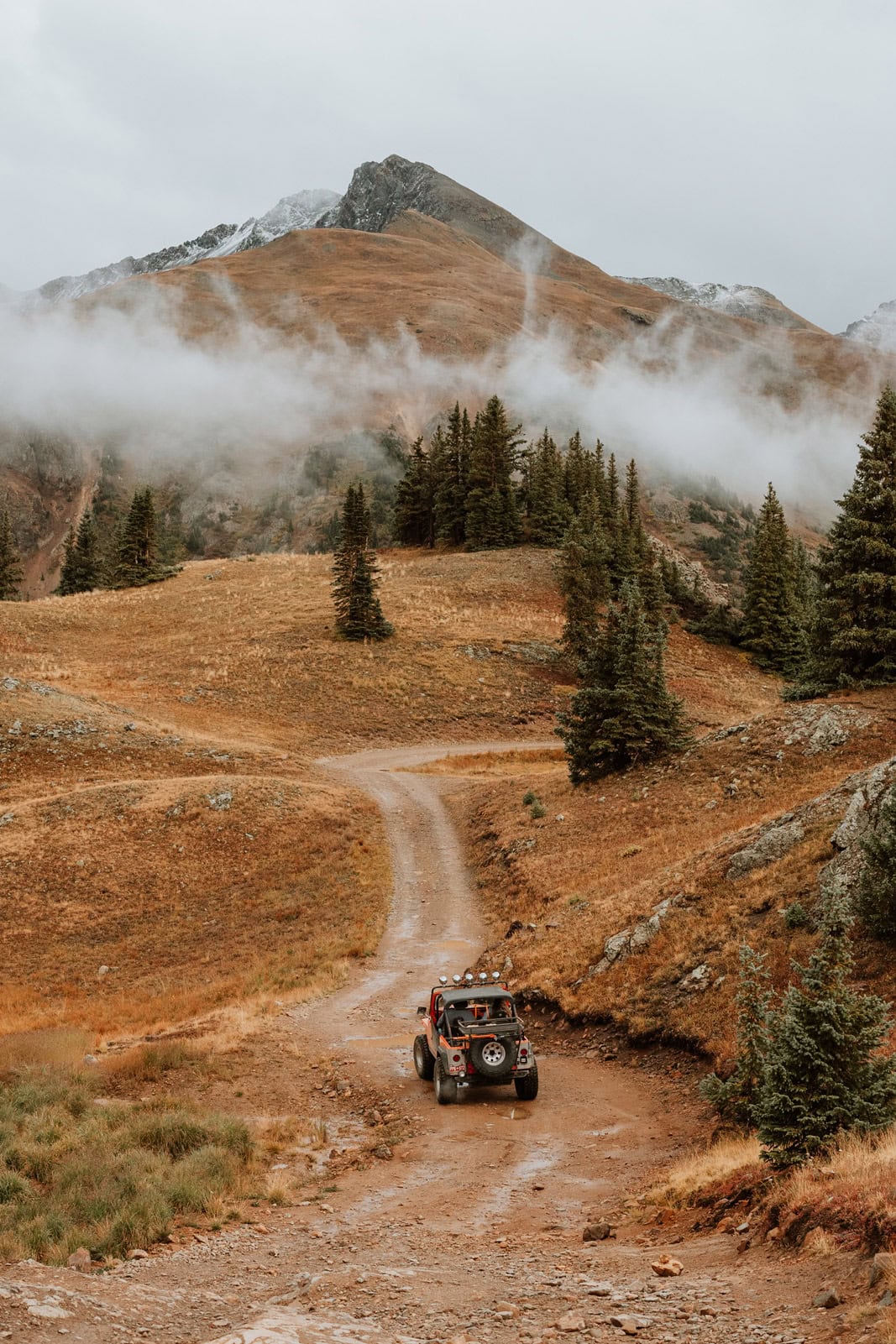 Jeep driving through rugged terrain with wide mountain views during a wedding day in Colorado.