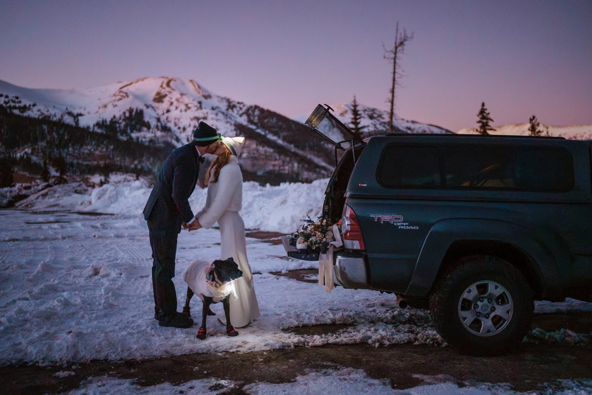 Post sunset winter elopement photo in Colorado with snow-covered mountains and headlamps