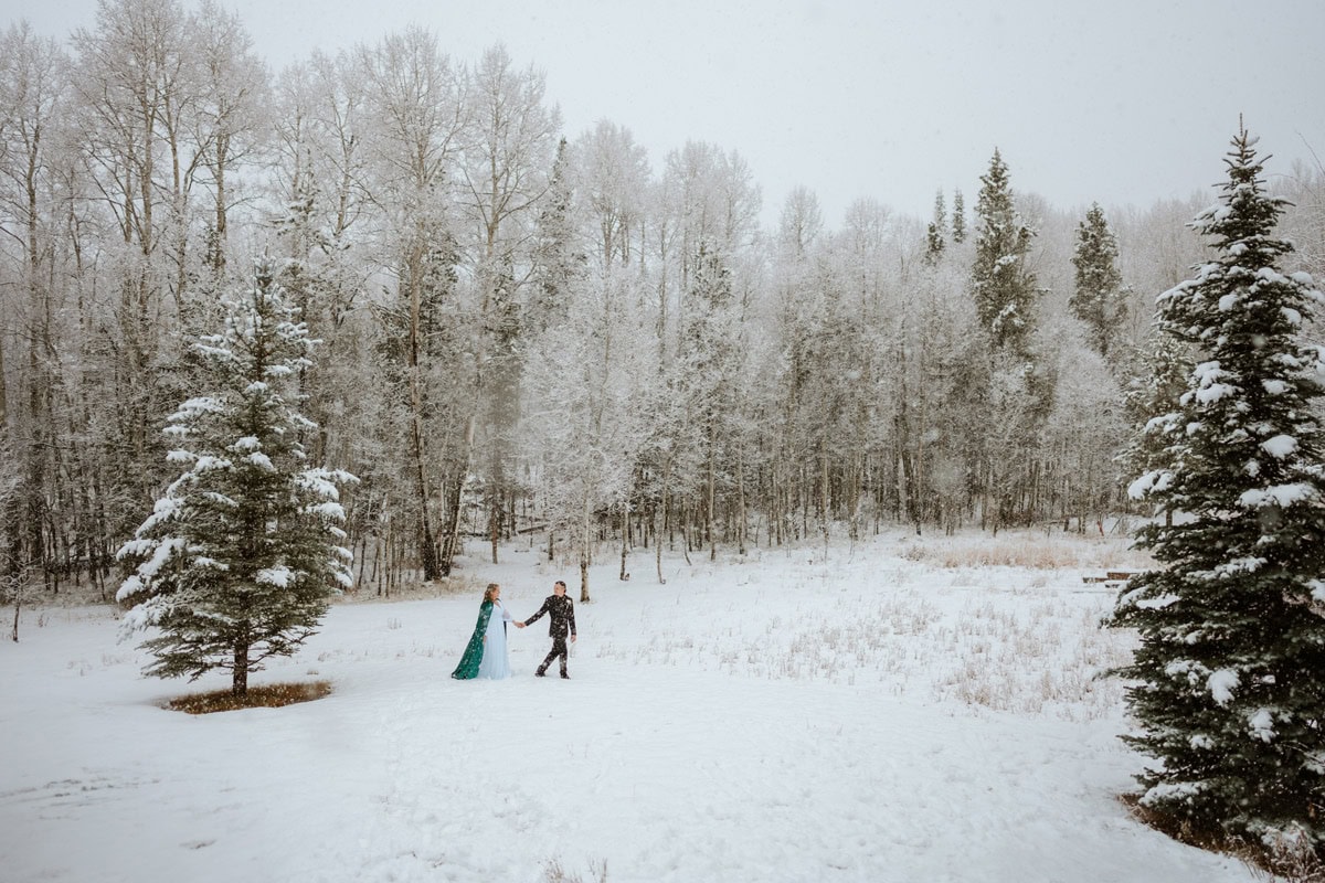 Couple walking together during an outdoor winter wedding in a snowy mountain setting