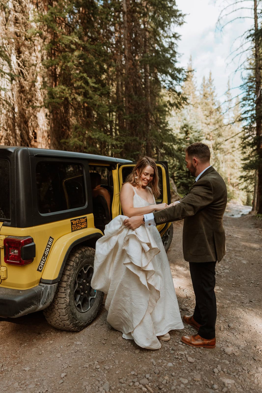 Bride stepping out of a yellow jeep during an elopement in the mountain town of Ouray, Colorado.