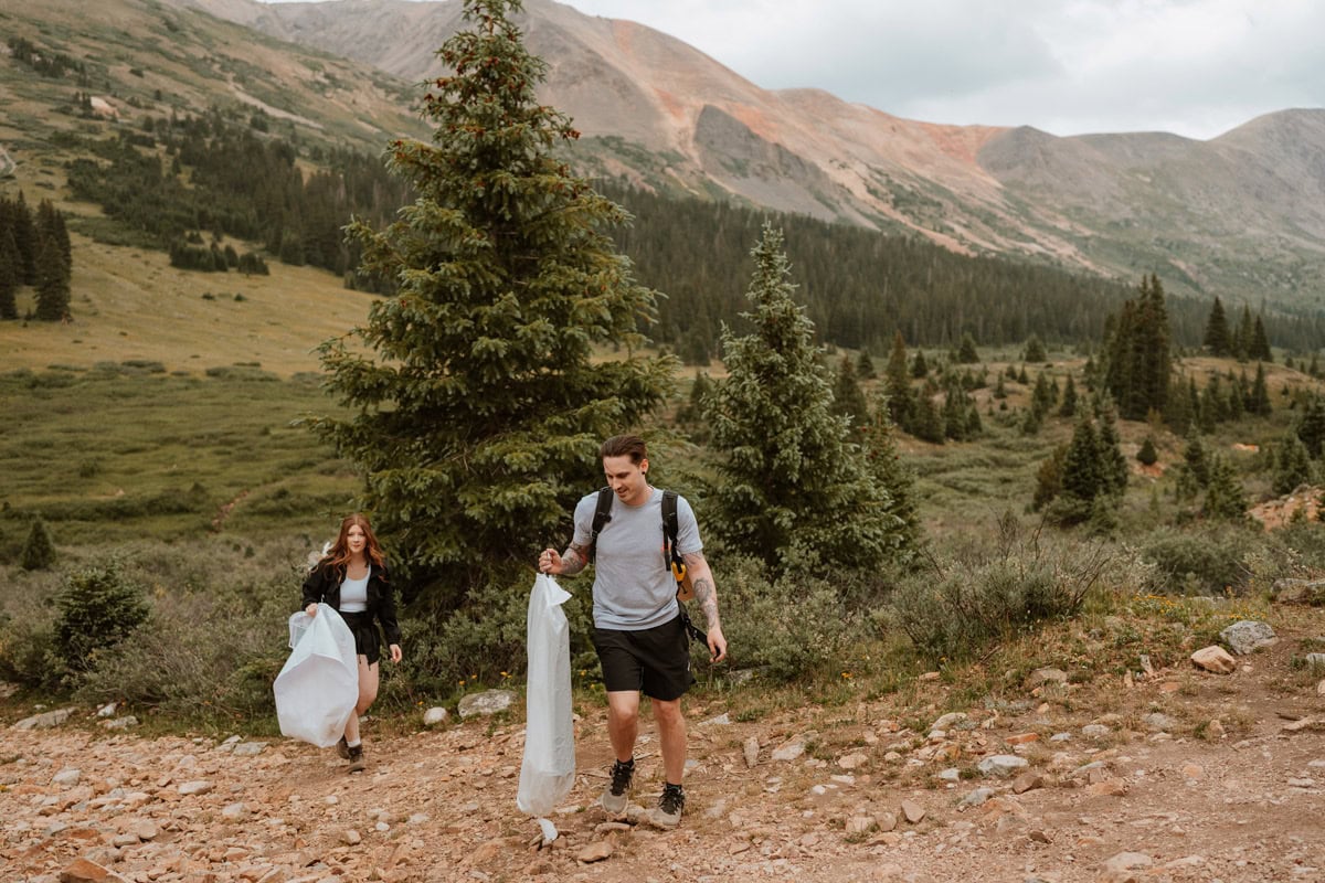 A couple hiking toward a high alpine basin under a dramatic cloudy sky for their Aspen elopement in Colorado.