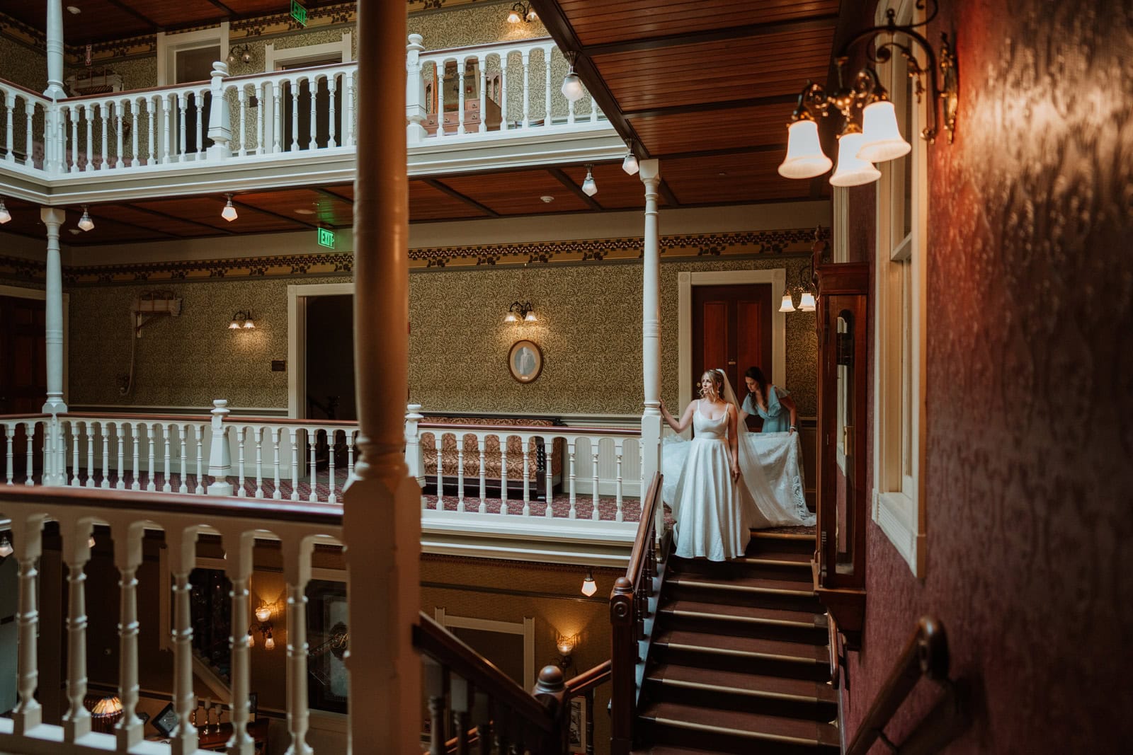 The bride and her bridesmaids walk down the staircase inside the ornate Beaumont Hotel in Ouray, captured during a timeless bridal wedding photo.