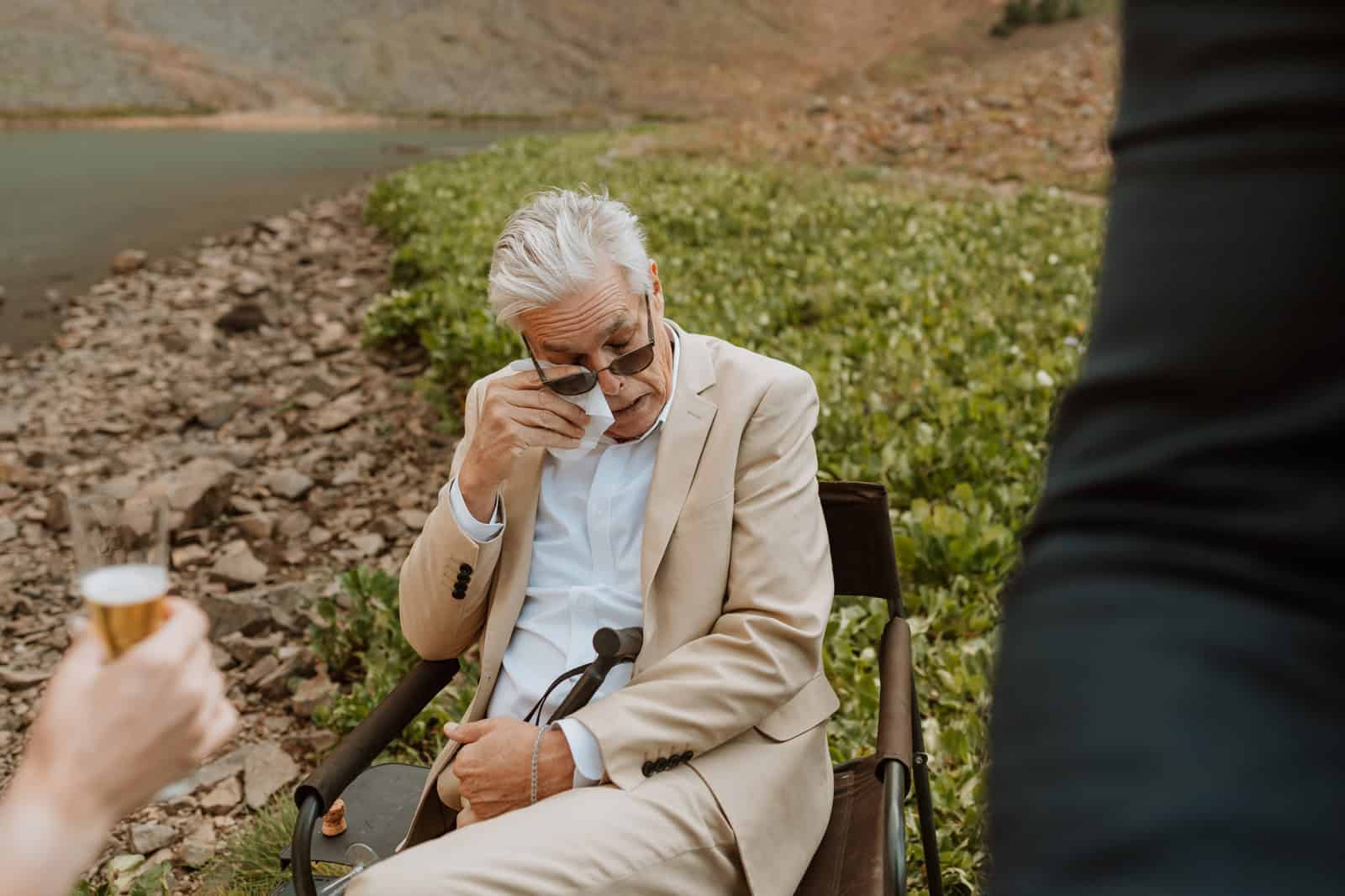 An emotional moment at a small wedding as a father of the bride wipes away tears during the wedding speeches in the San Juan Mountains.
