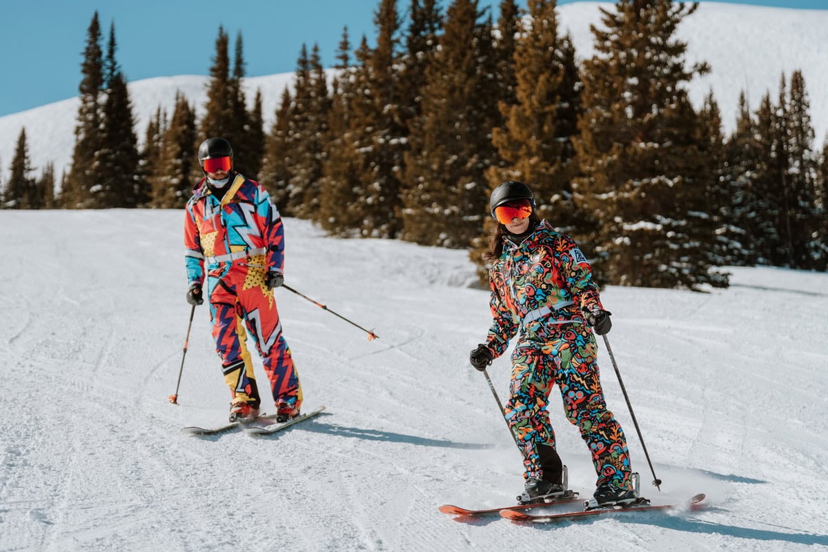 A newly engaged couple skiing together down a mountain at Copper Mountain, Colorado, after a successful surprise proposal.