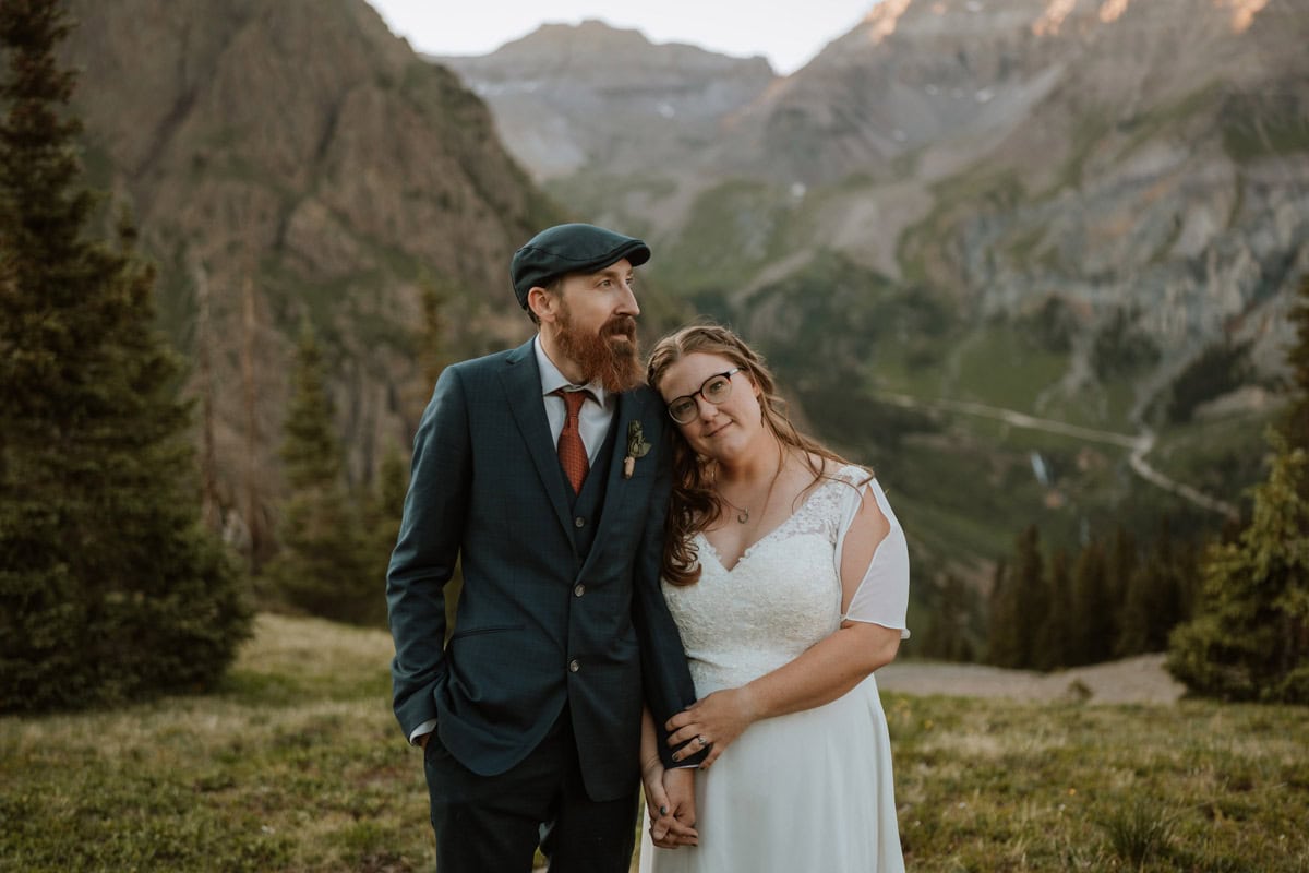 A close up portrait of a bride leaning on her groom's shoulder in front of a sweeping mountain valley during their adventurous Jeep destination vow renewal in Ouray, Colorado.