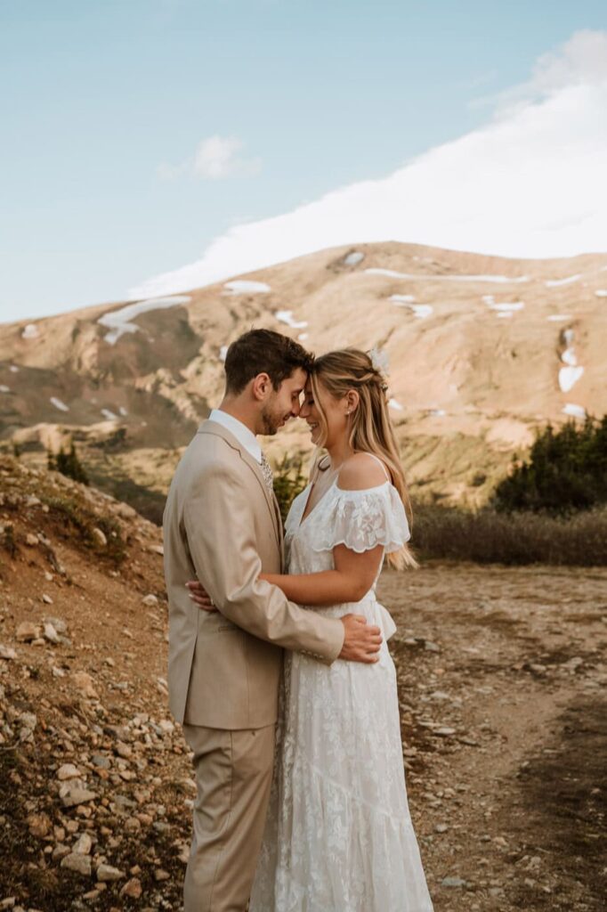 A bride and groom touch foreheads and smile at each other, enjoying a quiet moment during their Loveland pass elopement in the mountains.